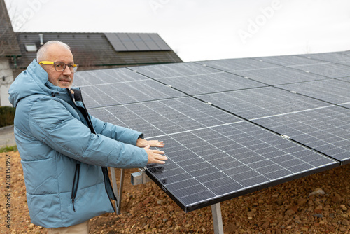Mature man standing near solar power panels. Close up of mans hands above solar power panels
