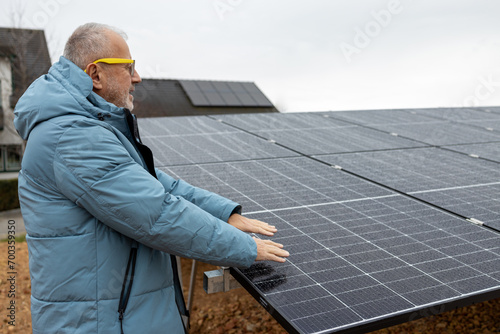 Mature man with solar power panels. Close up of mans hands above solar power panels