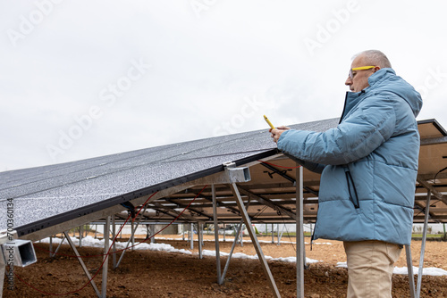 Mature man making a photo of solar power panels in his garden 