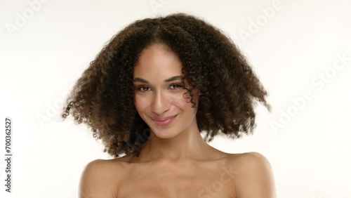 Cute slim happy woman of mixed race with tanned skin looking seductively, smiling, shaking her brown short curls in afro style isolated on white background. High quality 4k footage photo
