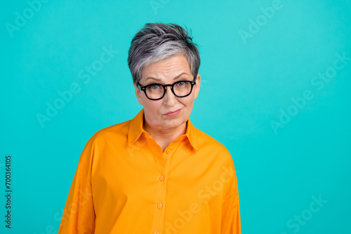 Photo of suspicious distrustful business woman old grandmother raise eyebrows wear orange shirt isolated on aquamarine color background photo
