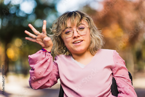 Young woman with cerebral palsy disability on wheelchair greeting and smile. Social inclusion