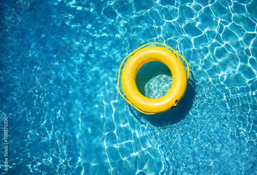 Top view of yellow swimming pool ring float in blue water. 