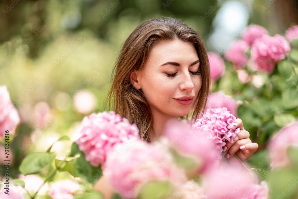 Hydrangeas Happy woman in pink dress amid hydrangeas. Large pink hydrangea caps surround woman. Sunny outdoor setting. Showcasing happy woman amid hydrangea bloom.