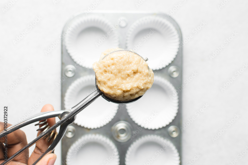 scooping vanilla almond muffins batter in a cupcake pan, top view of almond muffins batter, process of making almond muffins scooping vanilla almond muffins batter in a cupcake pan, top view of almond muffins batter, process of making almond muffins