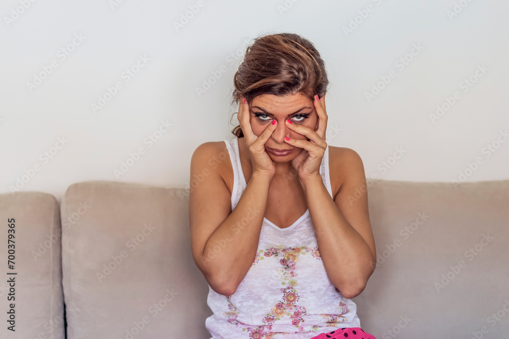 Fototapeta premium Unhappy Lonely Depressed Woman At Home. Sad Depressed Woman Touching Her Forehead And Looking Down, Stress And Exhaustion Concept.
