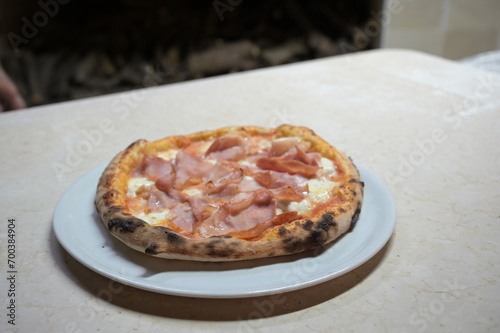pizza con mozzarella e prosciutto cotto sul bancone di una pizzeria italiana