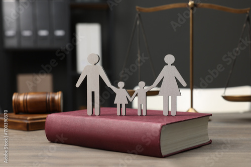 Family law. Figure of parents with children, book, scales of justice and gavel on wooden table