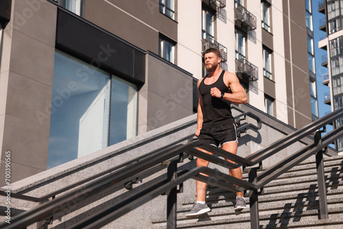 Man running down stairs outdoors on sunny day, low angle view. Space for text