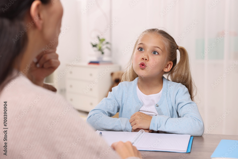 Dyslexia treatment. Speech therapist working with girl at table in room Dyslexia treatment. Speech therapist working with girl at table in room