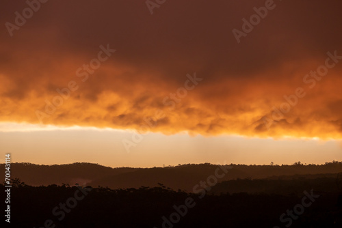 Photograph of a bright orange sunset sky over a large valley after a thunderstorm in The Blue Mountains in New South Wales in Australia