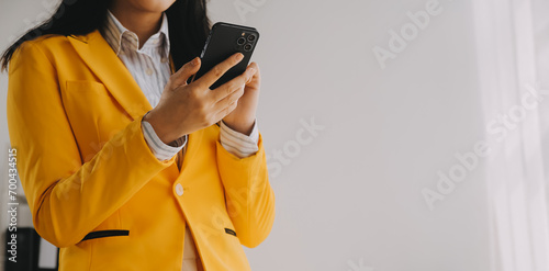 Young smiling business woman using smartphone near computer in office, copy space