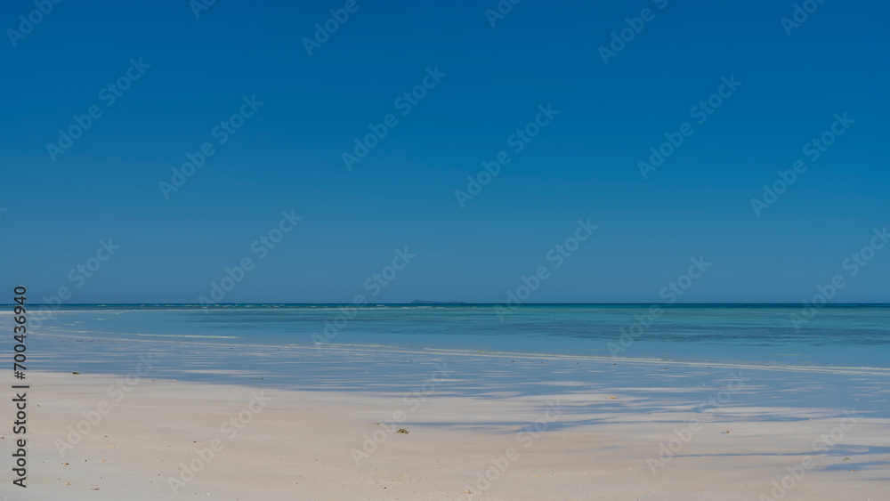 Beautiful minimalistic seascape. Endless aquamarine ocean, clear blue sky, white sandy beach. Copy Space. Madagascar. Nosy Iranja