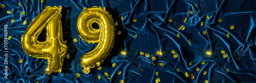 number forty nine, gold foil balloon number on a blue velvet background with confetti. Birthday greeting card, inscription 49. Anniversary event. Banner. Stylish gold numeral, bright shiny. photo