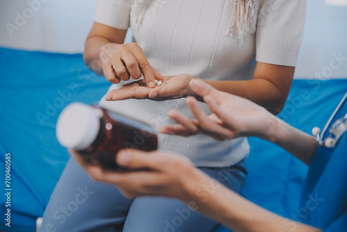 Asian woman nurse holding a medicine bottle and telling information to Asian senior woman before administering medication. Caregiver visit at home. Home health care and nursing home concept.
