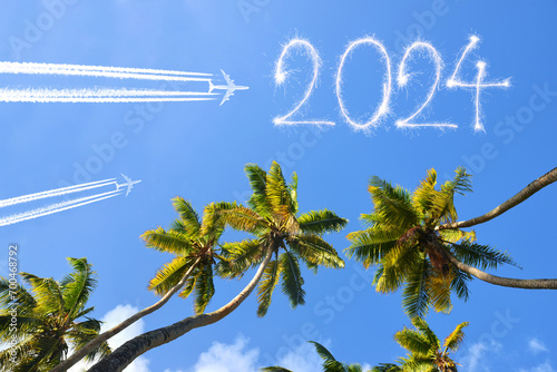 Happy New Year concept. Flying airplanes and 2024 writen with sparklers on blue sky. photo