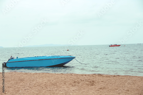 Blue boat moored in sea beach on sky and mountain view background © Amphawan