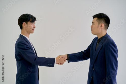 Asian businessmen are shake hand in formal suit on white background.