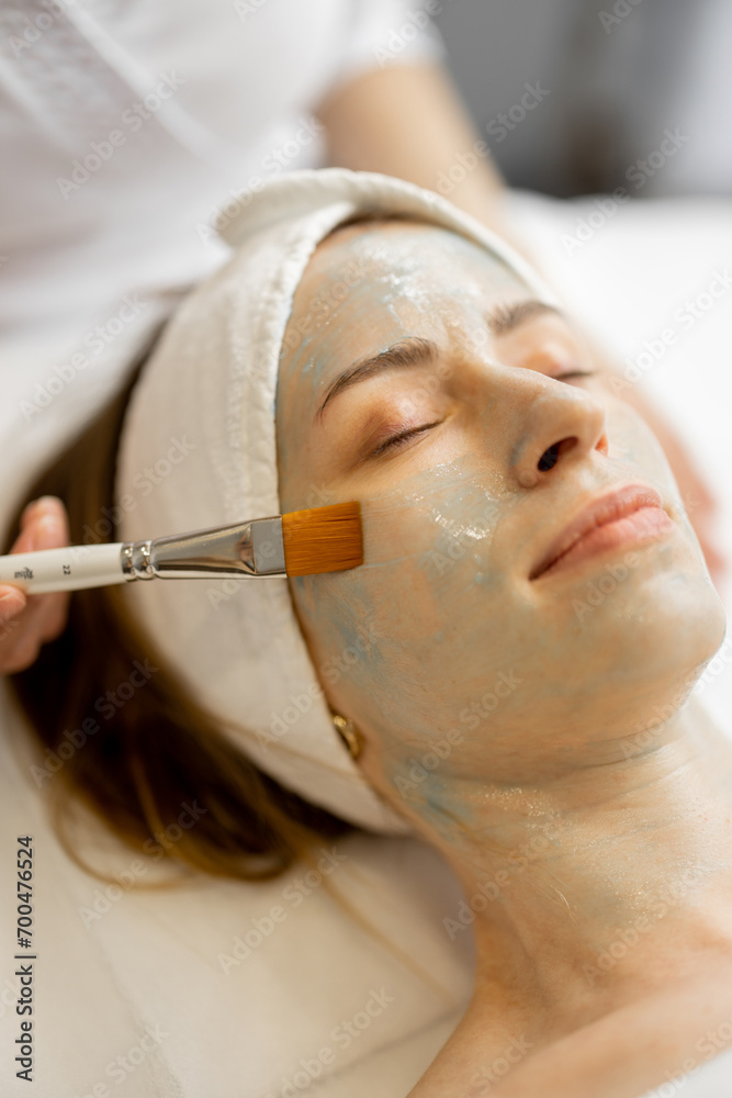 Applying beauty mask with a brush to a woman's face in beauty salon, close-up. Face care concept and beauty procedures