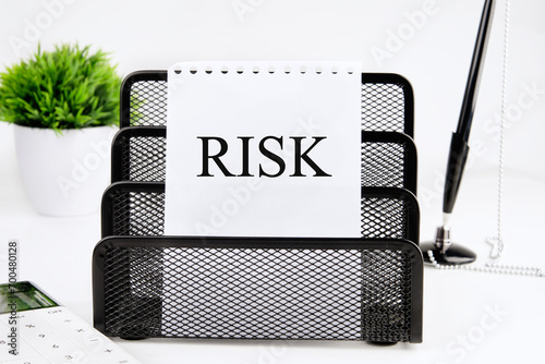 RISK A word written on a piece of paper from a notebook on a stand on a white background photo