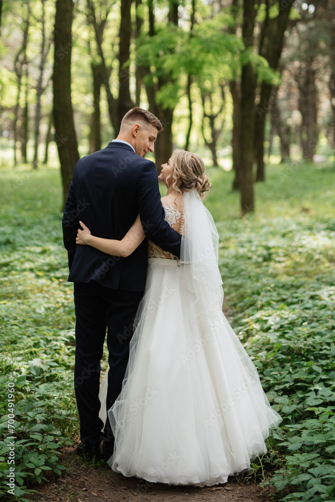the groom and the bride are walking in the forest