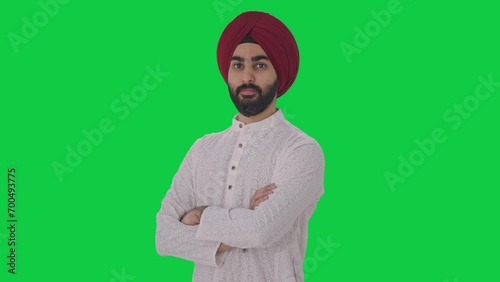 Portrait of Confident Sikh Indian man standing crossed hands Green screen