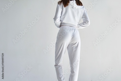 Back view of a young woman wearing white minimalist sweatpants. Step into Comfort with a Chic White Outfit Perfect for Casual Elegance. Sportwear mock-up. Girl in white pants. photo