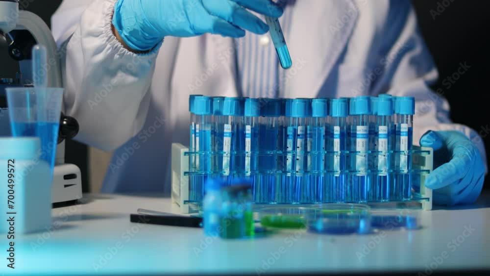 Scientist analyzes a colored liquid to extract the DNA and molecules in the test tubes. Scientists test the chemical reactions of the solution and test biological fluids in test tubes. Scientist analyzes a colored liquid to extract the DNA and molecules in the test tubes. Scientists test the chemical reactions of the solution and test biological fluids in test tubes.