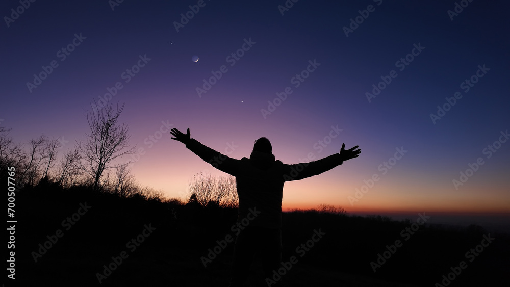 Man with arms wide open enjoying outdoors under stars, planets and Moon..