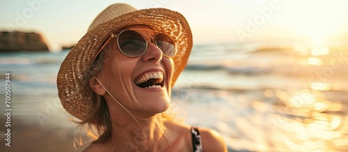 Cheerful mature woman running on the beach on a sunny day Beautiful middle aged woman laughing being active and having fun during summer vacation Energetic lady spending her free time by the se #700507944