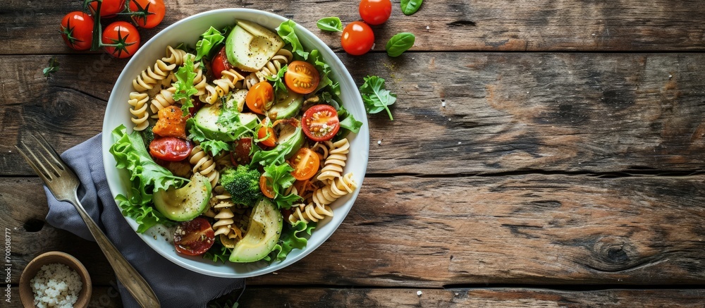 Healthy Chicken Pasta Salad with Avocado Tomato and olive oil and vinegar dressing in white bowl on white wood table vertical view from above free space. Creative Banner. Copyspace image