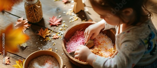 Fototapeta Naklejka Na Ścianę i Meble -  Child hands creating autumn tree with colored rice and natural materials Toddler filled the leaves with yellow and orange rice Montessori material Sensory play and fall nature crafts. Creative Banner