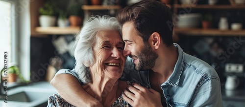 Affectionate happy young man cuddling smiling beautiful senior older mother enjoying dreamy mindful moment at home involved in pleasant trustful conversation visualizing future family relations
