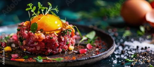 Gourmet tartar raw from beef fillet with yellow of the egg and vegetable as closeup on modern design dish. Creative Banner. Copyspace image photo