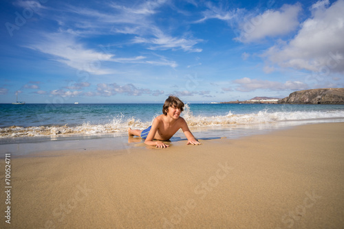 Portrait of a teenager lying on the sandy shore of the ocean.