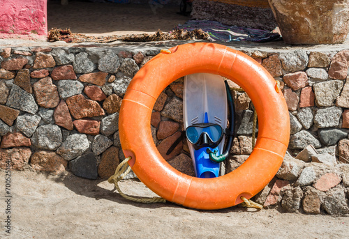 flippers with swimming mask and an orange life preserver against a stone wall in Egypt