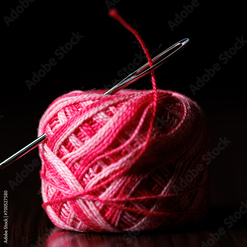 A skein of colored melange threads with a needle stuck into it. Selective focus.