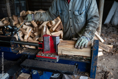 Fotografía Man with work gloves cuts firewood with hydraulic log splitter closeup