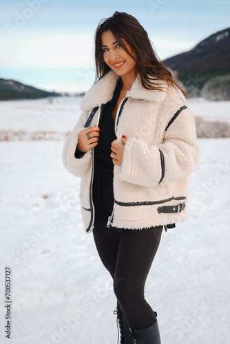beautiful young girl wearing a winter jacket outdoors in front of a snowy landscape