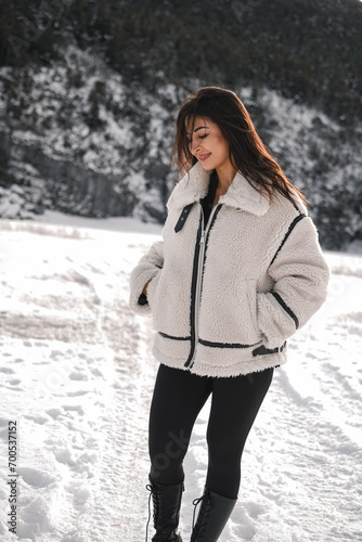 beautiful young girl wearing a winter jacket outdoors in front of a snowy landscape