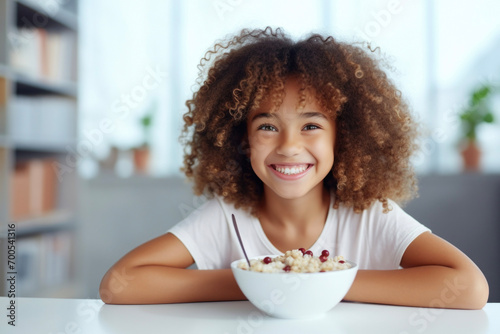 Black little girl having breakfast in a light kitchen