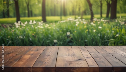  a wooden table sitting in front of a forest filled with green grass and white daffodils  with the sun shining through the trees in the middle of the background.