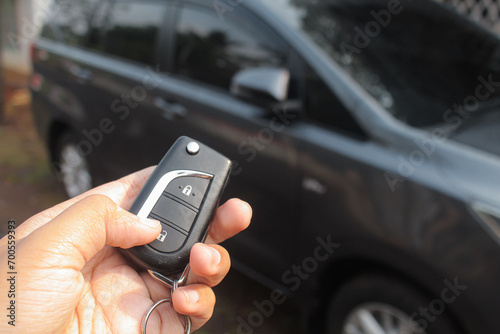 Driver pressing car lock or unlock alarm key and pointing it to his car