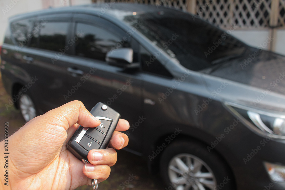 Fototapeta premium Driver pressing car lock or unlock alarm key and pointing it to his car