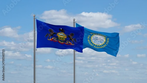 South Dakota and Pennsylvania US state flags waving together on cloudy sky, endless seamless loop photo