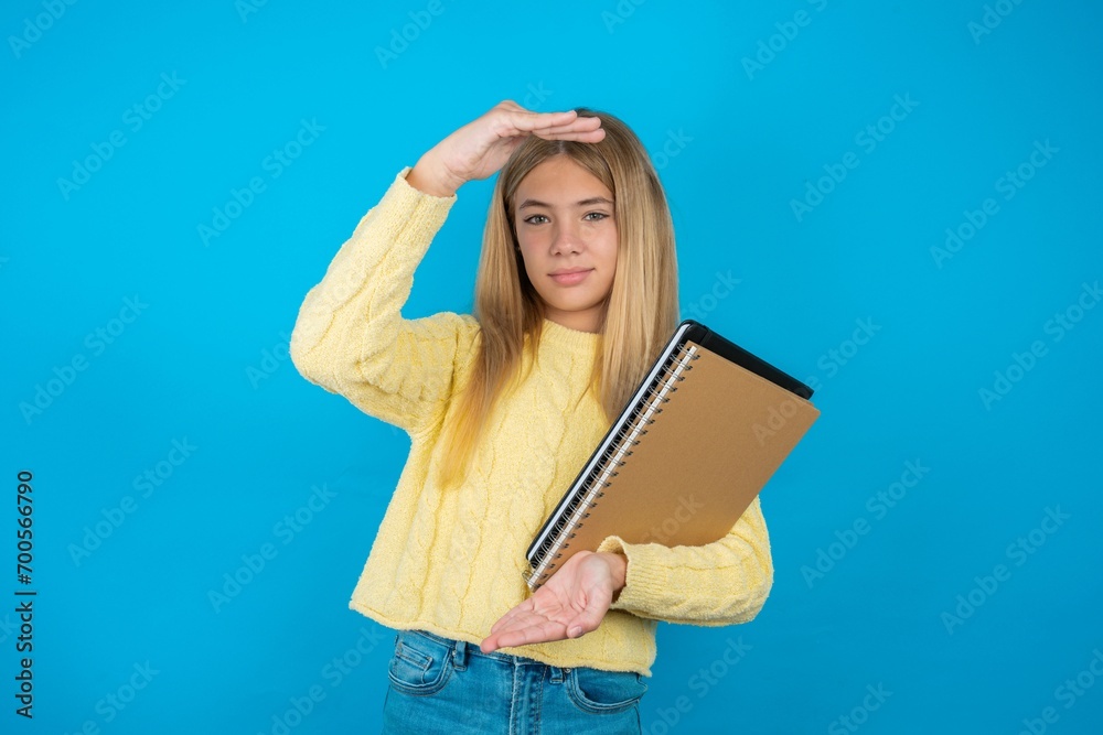 beautiful caucasian teen girl wearing yellow sweater gesturing with hands showing big and large size sign, measure symbol. Smiling looking at the camera. beautiful caucasian teen girl wearing yellow sweater gesturing with hands showing big and large size sign, measure symbol. Smiling looking at the camera.