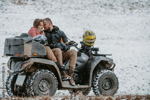  A romantic couple shares a tender embrace and kisses while joyously riding a quad through the snowy landscape, creating a magical and passionate moment amidst the wintry adventure