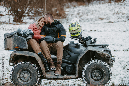 A romantic couple shares a tender embrace and kisses while joyously riding a quad through the snowy landscape, creating a magical and passionate moment amidst the wintry adventure