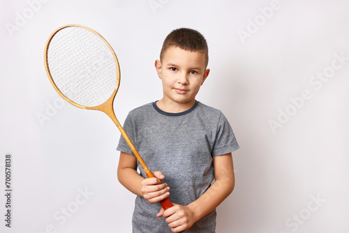 A smiling boy holds a badminton racket in his hands. Sports and physical education.