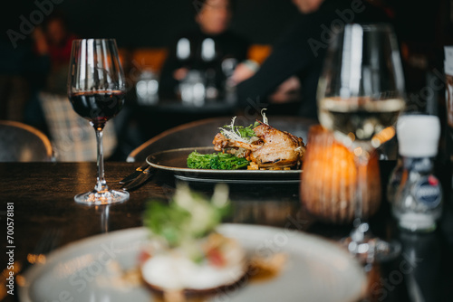 Culinary food plates on a table with glasses of wine.